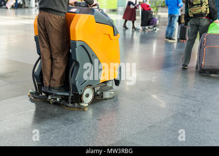 Man driving professional floor cleaning machine at airport or railway station.  Floor care and cleaning service agency Stock Photo