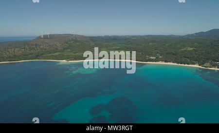 Aerial view of beautiful tropical beach Saud with turquoise water in blue lagoon, Pagudpud, Philippines. Ocean coastline with sandy beach and palm trees. Tropical landscape in Asia. Stock Photo