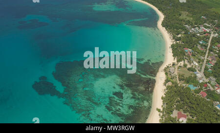 Aerial view of beautiful tropical beach Saud with turquoise water in blue lagoon, Pagudpud, Philippines. Ocean coastline with sandy beach and palm trees. Tropical landscape in Asia. Stock Photo