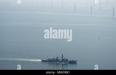 Aerial photo of Royal Navy Frigate passing wind turbines Liverpool Bay Stock Photo