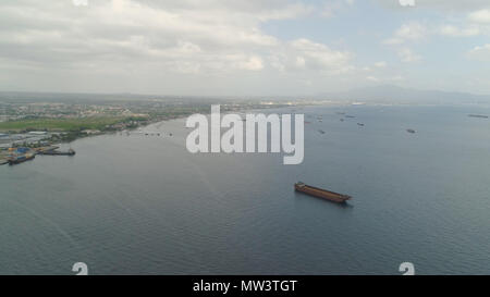 Aerial view cargo and merchant ships in harbor. trading vessels in the bay awaiting loading and unloading at the seaport. Batangas, Philippines. Stock Photo