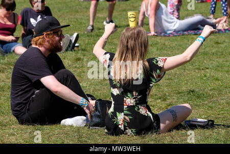 Back view of woman  sitting balancing Bestival paper disposable beer cup on her head at Common People Festival May 27th 2018 Stock Photo