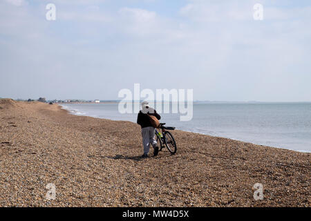 Angler wheeling his bicycle along the beach between Bawdsey and Shingle Street, Suffolk, UK. Stock Photo