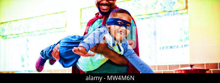 Son and father pretending to be a superhero in kitchen Stock Photo