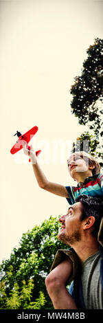 Boy with toy aeroplane sitting on fathers shoulders Stock Photo