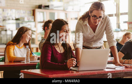 Portrait of young teacher helping a student during class. University student being helped by female lecturer during class. Stock Photo