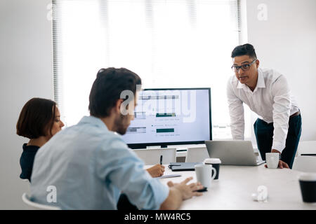 Businessman making a presentation to his colleagues in office. Office colleagues taking notes sitting at the conference room while listening to a pres Stock Photo