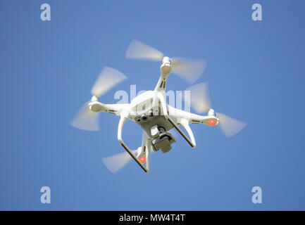 White drone with digital camera, filming from above. Proper for aerial surveillance. Clear blue sky background. Stock Photo