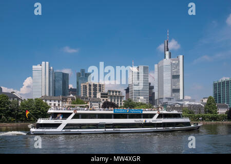 An opentop rivercruise boat takes tourists along the river Main to enjoy the City of Frankfurt am Main modern architecture skyline, Germany. Stock Photo