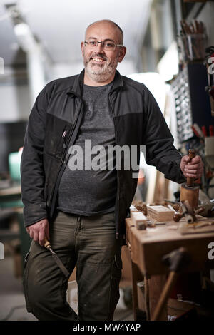 Cabinet Maker In His Workshop Smiling While Leaning Against His