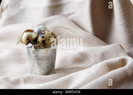 Fresh spotted quail eggs in a decorative metal bucket and some eggs on a homespun tablecloth, top view, close-up, vertical. Some copy space for your i Stock Photo