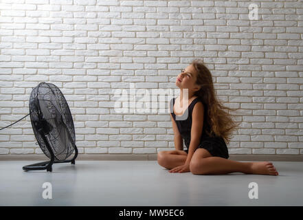 the girl is sitting in front of the fan Stock Photo