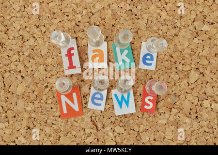 Words Fake News written with cut out magazine letters on bulletin board Stock Photo