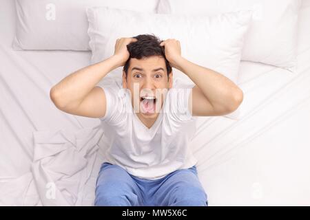 Young man suffering from insomnia sitting on a bed Stock Photo
