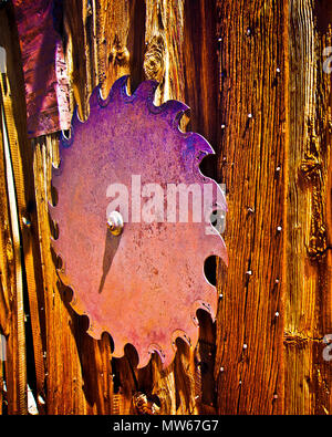 Colorful Artist vertical image of old rusty circular steel saw blade, bolted on to wooden wall dried out and aged. Stock Photo