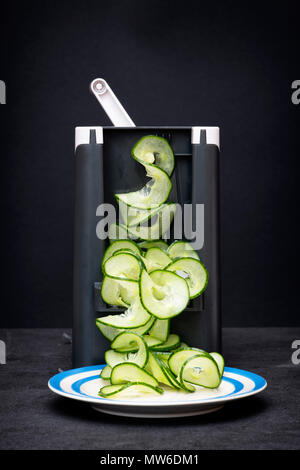 Spiralizing cucumber against a dark background Stock Photo