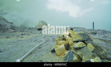 Extraction of sulfur in the crater of a volcano. Sulfur gas, smoke. Kawah Ijen, crater with acidic crater lake where sulfur is mined. Ijen volcano complex is a group of stratovolcanoes in the Banyuwangi Regency of East Java, Indonesia. Stock Photo