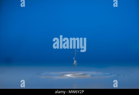 Water drop falling into water making a perfect droplet splash Stock Photo