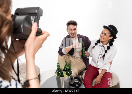 Cropped shot of woman with instant camera photographing happy young couple drinking beer together Stock Photo
