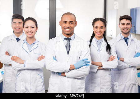 Team of young professional doctors standing together in laboratory, posing with arms crossed Stock Photo