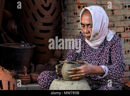 Old woman doing pottery work inside factory in Mu Ne, Vietnam Stock Photo