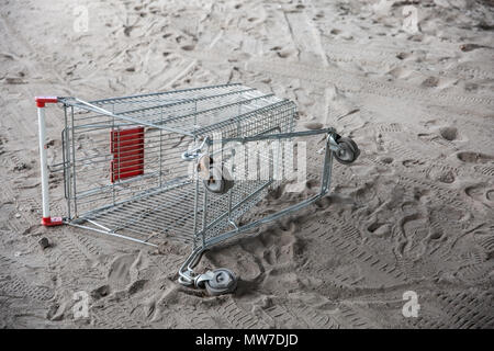 Close up of supermarket grocery inverted push cart for shopping on the sand. Concept of shopping. Stock Photo