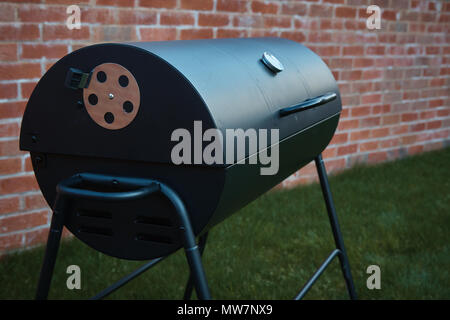 Black big barrel grill in the garden. Stock Photo