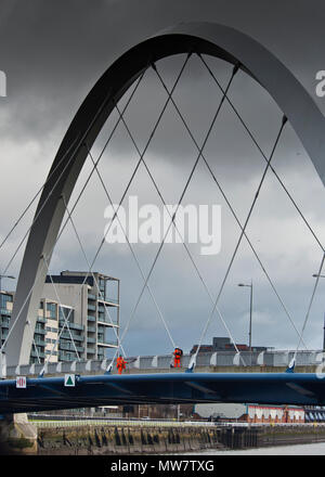 engineers wearing high visible safety suits harnessed up for safety inspecting The Clyde Arc (Squinty) Bridge over River Clyde Glasgow,
