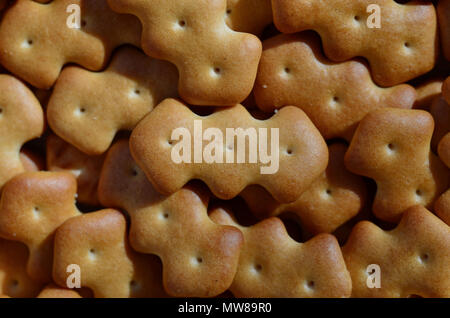 A huge bunch of salted biscuits of small sizes close-up. Macro shot of a large amount of salt cracker in golden yellow tones Stock Photo