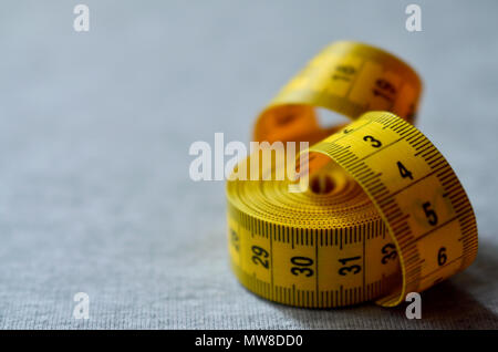 The measuring tape of yellow color with numerical indicators in the form of  centimeters or inches lies on a gray knitted fabric. Background image abou  Stock Photo - Alamy