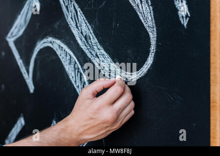 cropped shot of man writing 50% sale offer on chalkboard Stock Photo