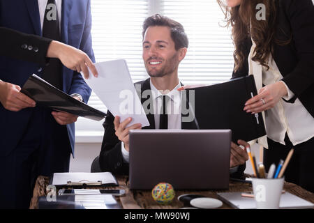 Young Businessman Looking At Document Shown By Partner Stock Photo