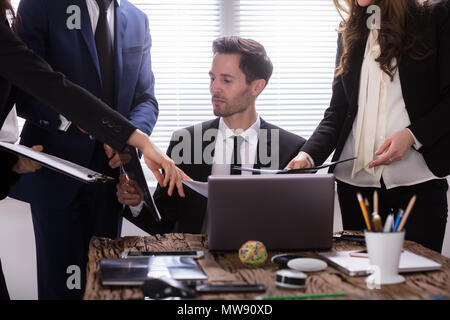 Young Businessman Looking At Document Shown By Partner Stock Photo