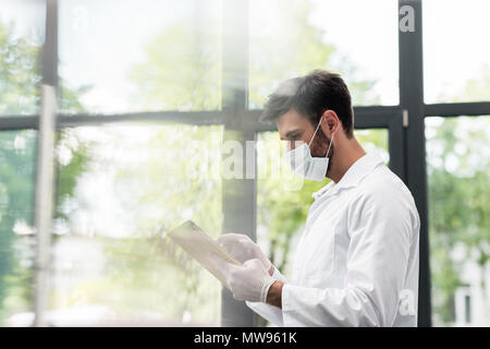 Male scientist in protective workwear using digital tablet in laboratory Stock Photo