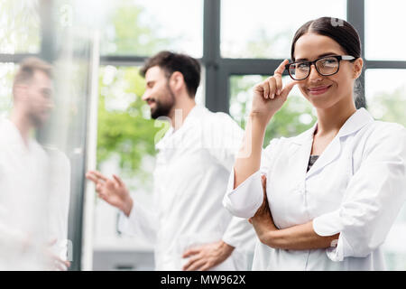 Team of professional scientists in white coats smiling while standing in laboratory Stock Photo