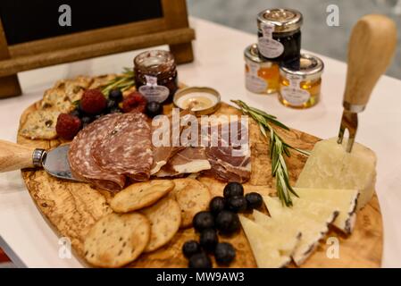 Charcuterie display of salami, cheese, raspberries, grapes, jam, marmelade and crackers on wooden cutting board. Stock Photo