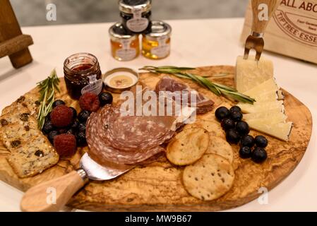 Charcuterie display of salami, cheese, raspberries, grapes, jam, marmelade and crackers on wooden cutting board. Stock Photo