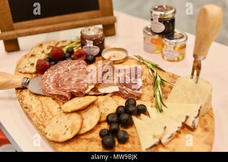 Charcuterie display of salami, cheese, raspberries, grapes, jam, marmelade and crackers on wooden cutting board. Stock Photo