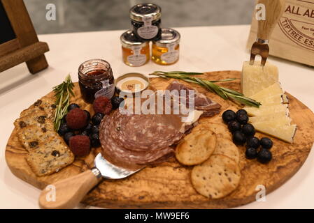 Charcuterie display of salami, cheese, raspberries, grapes, jam, marmelade and crackers on wooden cutting board. Stock Photo