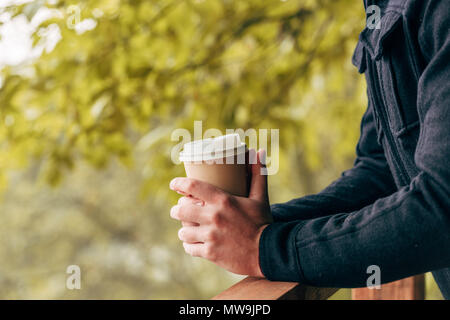 cropped shot of young man holding disposable coffee cup in autumn park Stock Photo