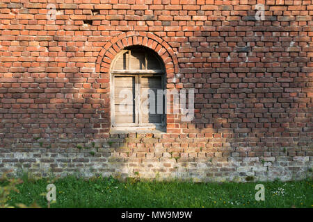 Old wooden arched window, shut down, red bricks vintage wall, farmhouse, Europe Stock Photo