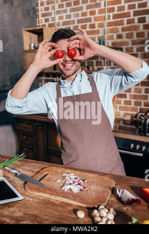 funny young man covering eyes with tomatoes Stock Photo