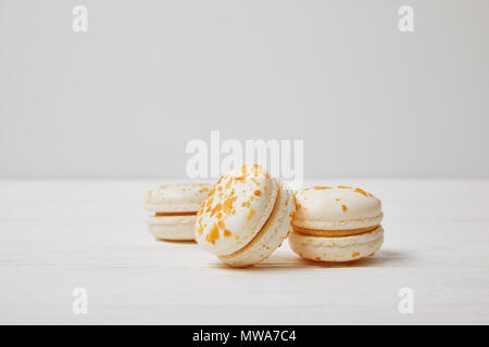 closeup shot of three macarons on white wooden table Stock Photo
