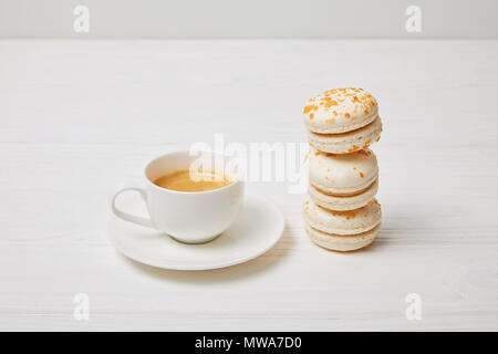 closeup shot of coffee cup and stack of macaroons on white wooden table Stock Photo