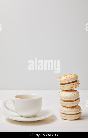 closeup shot of coffee cup and stack of macarons on white wooden table Stock Photo