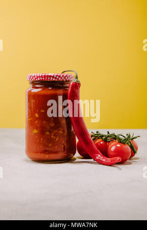 canned ketchup with chilli pepper and cherry tomatoes on concrete surface Stock Photo