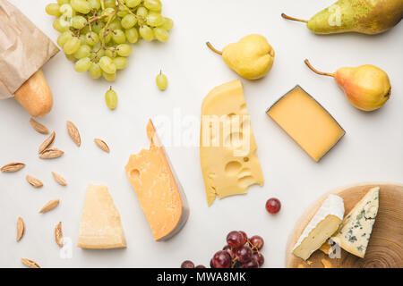 Top view of different types of cheese, grapes, pears, almond and baguette on white Stock Photo