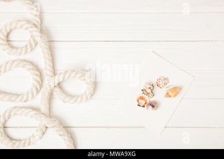 top view of white nautical rope and seashells on empty paper on wooden surface Stock Photo