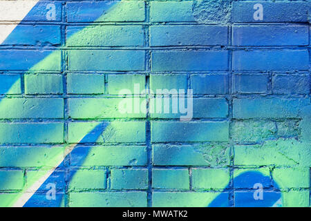 Several painted bricks in blue and yellow colors on an old dirty wall, as graffiti. Colorful grunge texture of wall. Abstract modern background Stock Photo