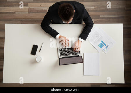 Businessman working on laptop computer sitting at desk, top view Stock Photo